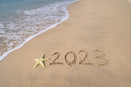 2023 hand written with starfish in sand on a beautiful beachの写真素材