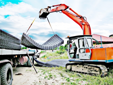 Excavator busy unloading the wire mesh from the trailerのeditorial素材