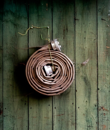 Fire hose hanging on a wooden wallの写真素材