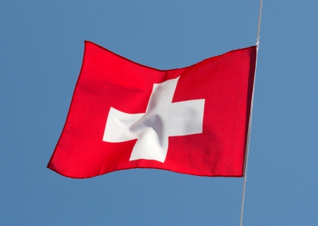Swiss flag in the wind against the skyの写真素材