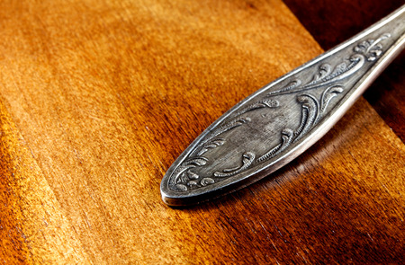 Handle silver spoon lying on a wooden surfaceの写真素材