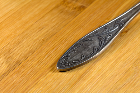 Handle silver spoon lying on a wooden surface
