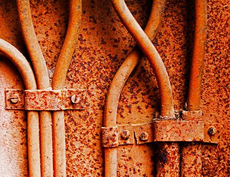 Old electrical cables on a rusty iron wall