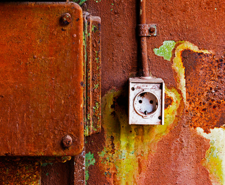 Old electrical outlet on a rusty iron wallの写真素材