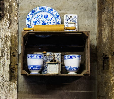 Old coffee grinder with dishes in the cupboard on the wallの写真素材