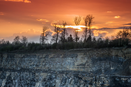 Sunset over the forest and the steep cliff of the quarryの写真素材