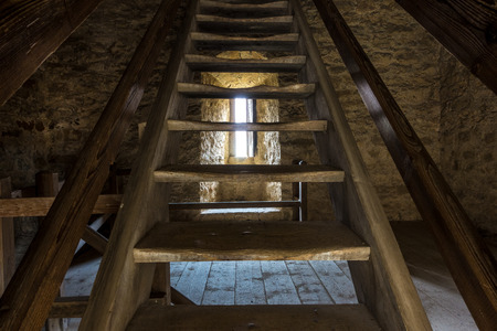 Dark room with stone walls window and wooden staircaseの写真素材