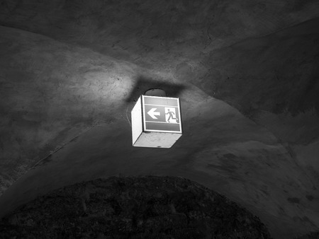 The illuminated green exit sign in dark room .の写真素材