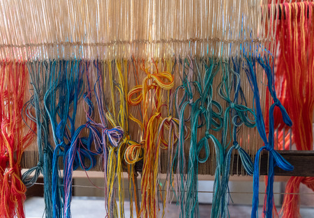 Colored threads of an ancient wooden loom .の写真素材