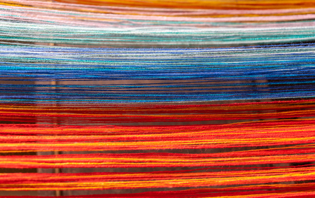 Colored threads of an ancient wooden loom .の写真素材