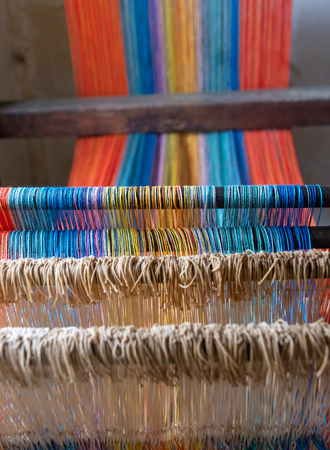 Colored threads of an ancient wooden loom .の写真素材