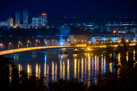 Night view of the Podil and Obolon districts of the city of Kyiv and Dnipro River Dnieper with various bridges. Ukraine, July 2020. High quality photoの写真素材