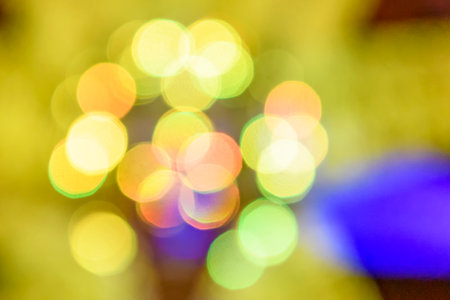 Multicolored holiday lights in defocus. Blurred abstract illuminate decorative lights with bokeh in...