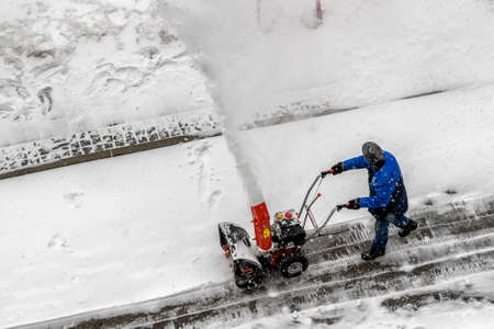 City worker clear snow with a snow thrower on the street during a snowfall in Kyiv, Ukraine, February 8, 2021. High quality photoの写真素材