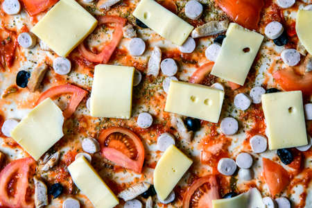 Italian pizza ready for baking. Dough, tomatoes, cheese, ham, bacon, olives.の写真素材