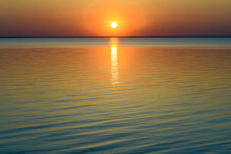 Bright beautiful sunset at the calm sea. Solar disk over water. High quality photoの写真素材