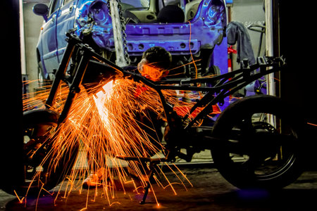 Welder repairs a motorcycle in a garage. Silhouette of a worker with a beam of sparks. ... High quality photoの写真素材