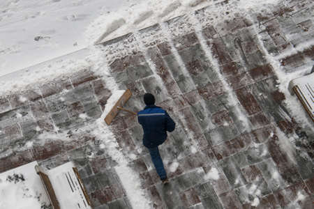City worker clear snow with a shovel on the street after a snowfallの写真素材