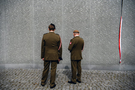 Polish servicemen stand near Memorial wall with the names of Poles, victims of Stalinist repressions...