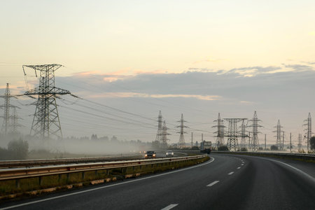 Metal supports of power lines at colorful sunset sunrise, foggy morning. High quality photoの写真素材