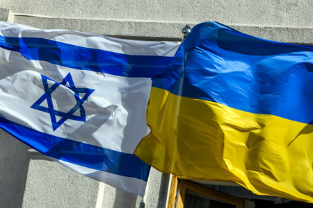 The national flags of Ukraine and Israel wave on flagpoles near an administrative building under...