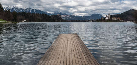Bled, Slovenia, 04 11 2018: View over Bled lake, a wooden jetty and the mountains in the backgroundのeditorial素材