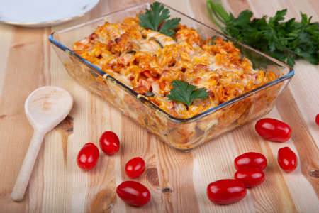 Fusili pasta baked with vegetables, tomatoes on a wooden tableの写真素材