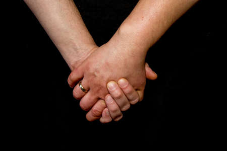 Muffled hands on a dark background. Visible wedding ring.の写真素材