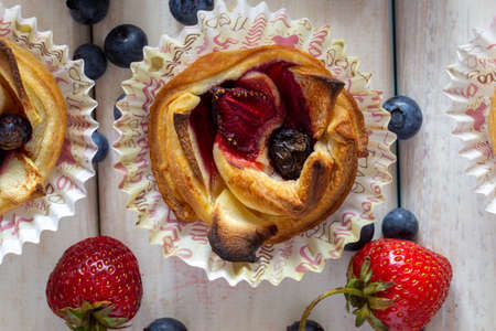 Tartlet with strawberries, apples, blueberries and cinnamon on a wooden background. Fresh and baked fruits.の写真素材