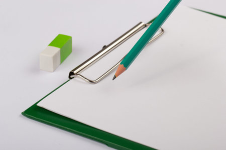Green blank notebook with pencil and eraser isolated on white.