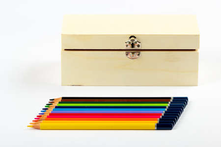 Stacked colored pencils next to a wooden box on a light background.の写真素材
