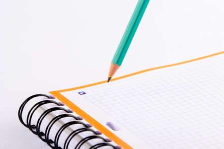 Green pencil writing in a checkered notebook. A card with an orange frame.の写真素材