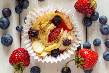 Tartlet with strawberries, apples, blueberries and cinnamon on a wooden background. Fresh and baked fruits.の写真素材