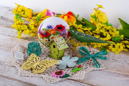 A spring arrangement of flowers with a candle, a wooden bird and a birdhouse.の写真素材