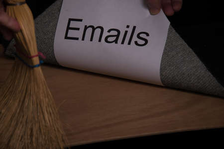 Hand sweeps a paper under a rug carpet on a wood grain table.の写真素材
