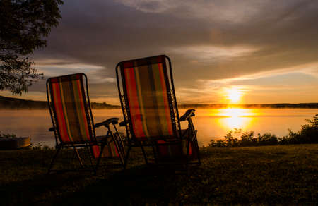 Vacation scene of chairs facing a lake in summertime.の写真素材