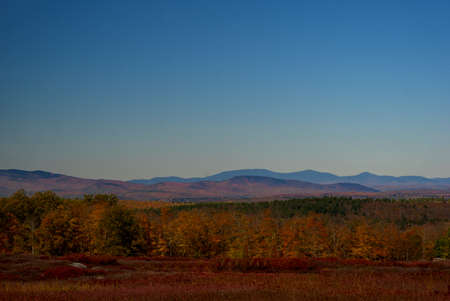 Fall scene of field and mountains and forest and blue skyの写真素材