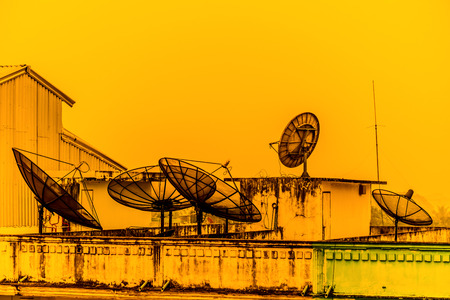 A few satellite dishes on a roof in the sunsetの写真素材