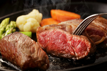 Beef steak on steel plateの写真素材
