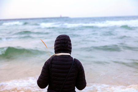 Woman walking alone on the beach, go straight to the sea and lighthouse