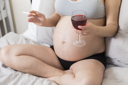 Pregnant woman smoking cigarette and drinking alcohol, Woman in pregnancy with tabacco and glass of wineの写真素材