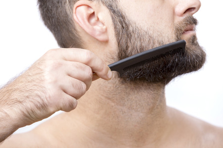 Man combing his beardの写真素材