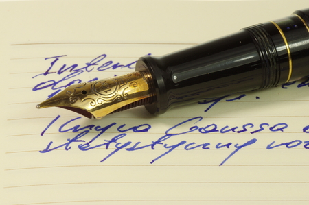 Fountain pen with gold, ornate nib on a notebook.の写真素材