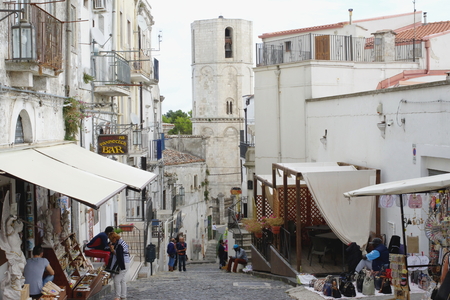 Monte Sant Angelo, Italy - September 11, 2015: center of the historic town on the Gargano Peninsula in the province of Foggia. On the historic street stalls with souvenirs. At the end of the street you can see the tower of the Shrine of Saint Michael the のeditorial素材