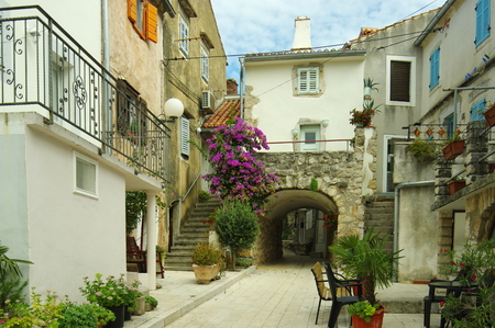 Omisalj, Croatia - September 20, 2016, a town situated on the northern coast of the island of Krk. The street in the old town with buildings typical for the region - courtyard decorated with flowers.のeditorial素材
