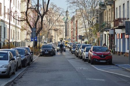 Cracow, Poland â November 07, 2018: Rajska street. Along the street there are historic tenement houses and parked cars. In the background you can see the church of the Carmelite Fathers.のeditorial素材