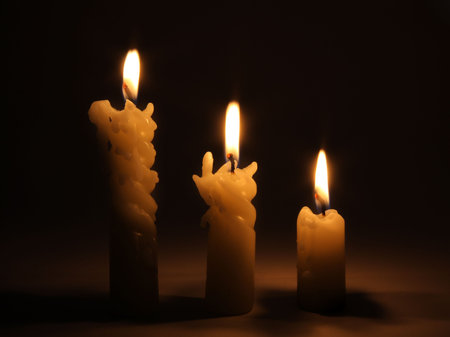 Three burning candles in darkの写真素材