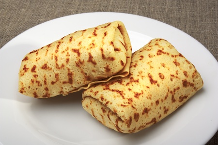 Pancakes with rolled up into a roll, on a white plateの写真素材