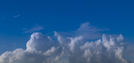 white cumulus clouds against a bright blue sky without the sunの写真素材