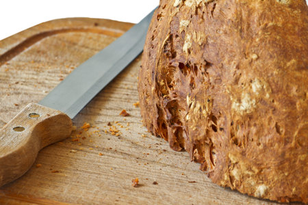 knife and a loaf of fresh bread with a crispy crust on a wooden board